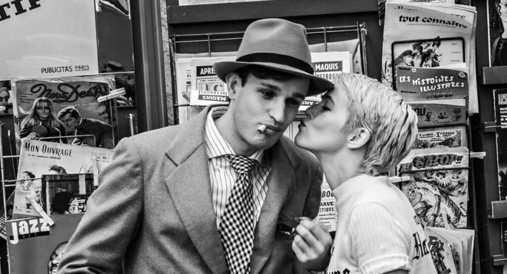 Zoey Deutch as Jean Seberg kisses Aubry Dullin as Jean-Paul Belmondo.